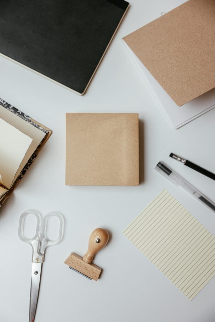 aerospace Flat lay of stationery items including notepad, pens, and scissors on a white desk.